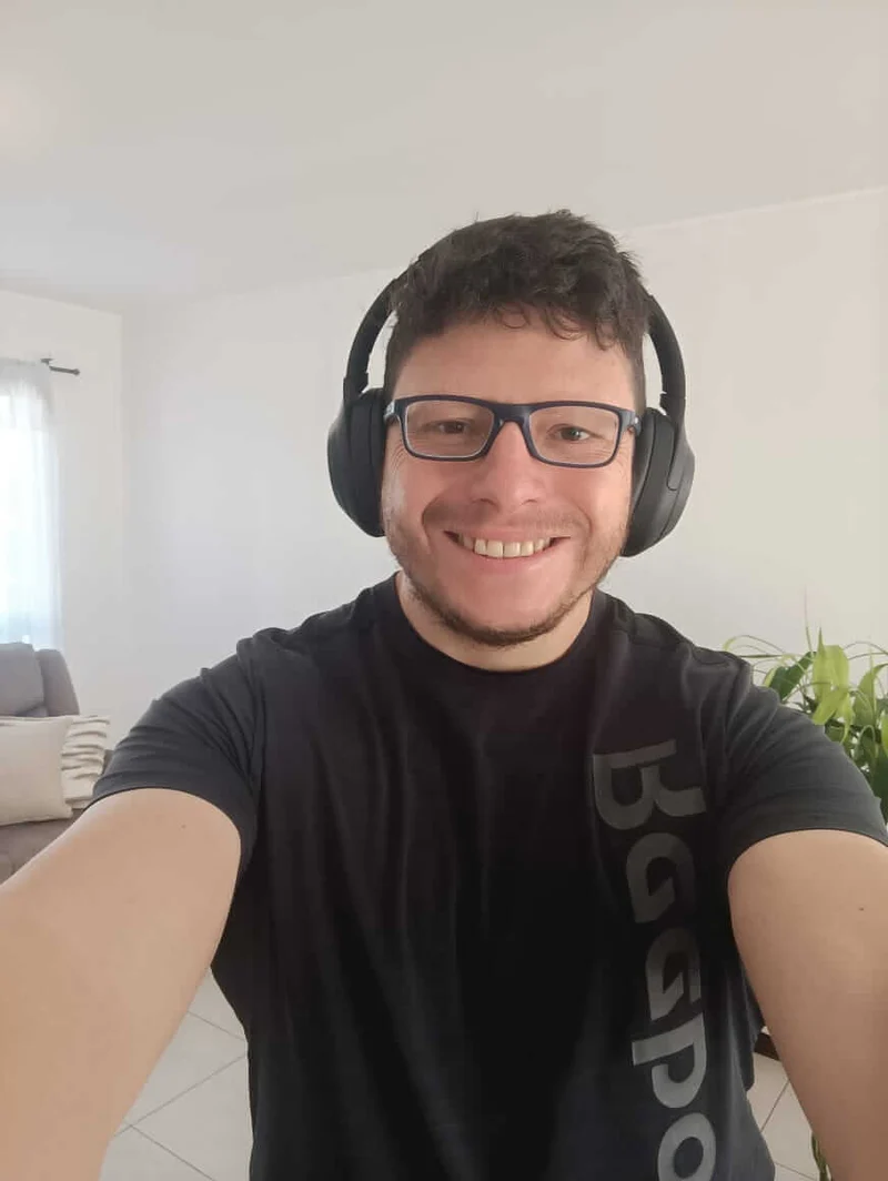 Carlos Nieto Herrera sonriendo con los audífonos Sony WH-1000XM4 puestos en su espacio de trabajo en casa